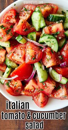 a salad with cucumbers, tomatoes and onions in a white bowl on a wooden table