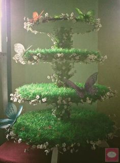 an aquarium with grass and butterflies on it's sides, in front of a window