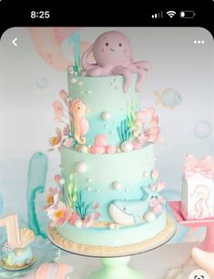 a three tiered cake decorated with an octopus and sea animals on it's side