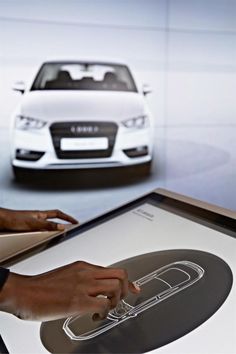 a person using a computer on top of a table with an image of a car in the background