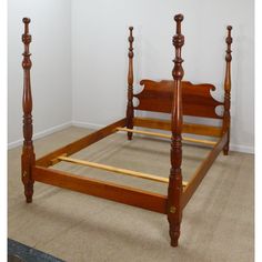 a wooden bed frame with four posts in a room