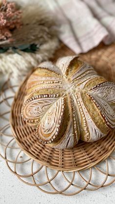 a loaf of bread sitting on top of a wicker basket next to a flower