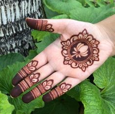 a woman's hand with henna on it and green leaves in the background