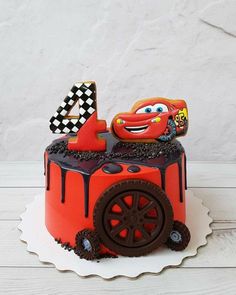 a birthday cake with the number four in the shape of a race car on top