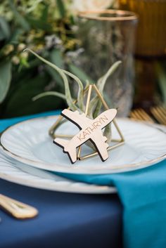 an airplane shaped place setting on a table with blue linens and gold cutlery