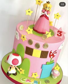 a pink cake decorated with mario and princess peaches, stars, and other decorations