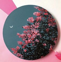 a circular painting with pink flowers and a moon in the sky on a blue background