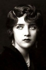 an old black and white photo of a woman with short hair looking at the camera