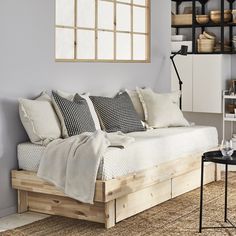 a bed with pillows and blankets on it in a room next to a wall mounted bookshelf