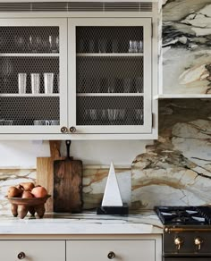 a kitchen with white cabinets and marble counter tops, including an oven top stovetop