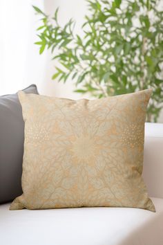 a close up of a pillow on a couch with a plant in the back ground