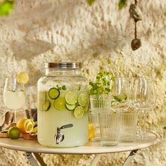 a table topped with lots of glasses filled with lemonade and cucumber slices