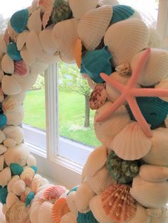 a wreath made out of seashells and starfish on a window sill