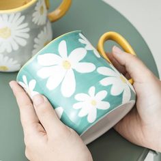 a person holding a coffee mug on top of a green table next to a yellow handle