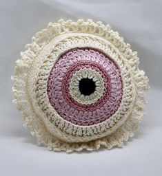 a crocheted round object with a black hole in the center on a white background