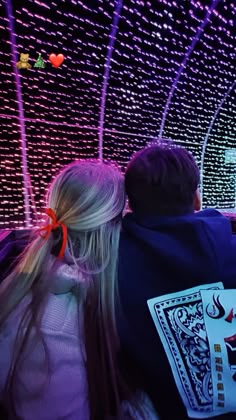 two people sitting in front of a computer screen with playing cards on it and colorful lights behind them