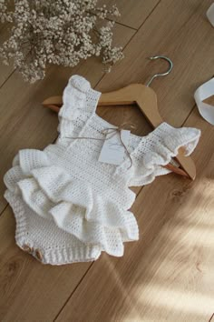 a white knitted romper and shoes on the floor