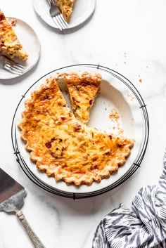 a piece of quiche on a plate with a fork and knife next to it