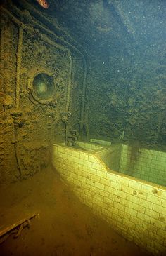 an underwater view of a bathtub in the middle of a dirty room with yellow tiles