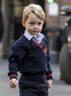 a young boy is walking down the street with his hand in his pocket and looking at the camera