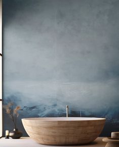 a bathtub in front of a wall painted with blue and white paint, sitting on a table