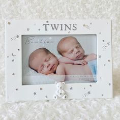 two twin babies laying next to each other in a white frame with stars on it