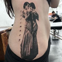 a woman with a tattoo on her stomach has an image of two women hugging each other