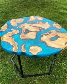 a table made out of wood with blue paint on it and black metal legs in the grass