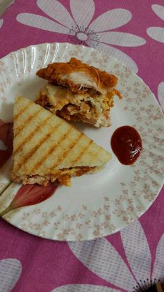 a grilled sandwich on a plate with ketchup and another sandwich in the background