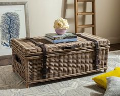 a wicker trunk sitting on top of a rug next to a vase with flowers