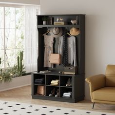 a room with a couch, chair and coat rack filled with clothes on shelves next to a window