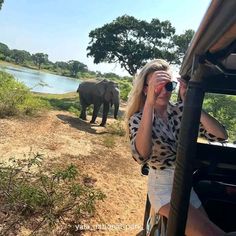 a woman is looking through binoculars at an elephant