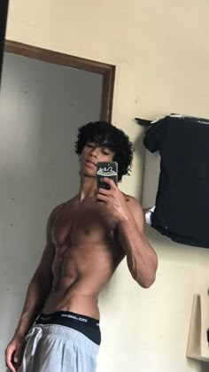 a shirtless man taking a selfie in front of a mirror with his cell phone