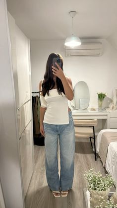 a woman is taking a selfie in her bedroom while wearing high waisted jeans