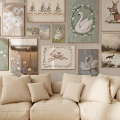 a living room filled with lots of pictures on the wall above a white couch covered in pillows