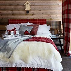 a bed with red and white plaid sheets, pillows and blankets on top of it