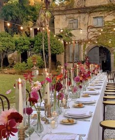 a long table is set up with flowers and candles for an outdoor dinner in the garden