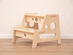 a wooden step stool sitting on top of a hard wood floor next to a white wall