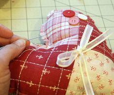 someone is making a red and white heart pillow with buttons on it's sides