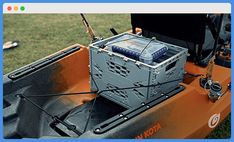 an orange and black boat with some electronics on it's back end in the grass