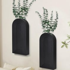 two black wall mounted planters with plants in them