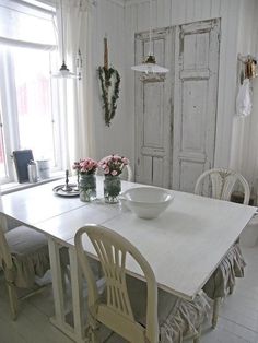 a white table and chairs with flowers in vases on the table next to it