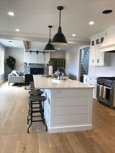 a large kitchen with an island and bar stools in the middle of the room