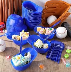 a table topped with blue bowls filled with desserts and baseball mitts on top of it