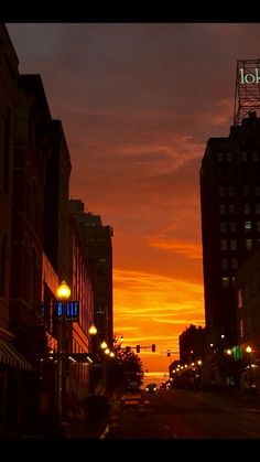 the sun is setting over some buildings and street lights in an urban area with tall buildings