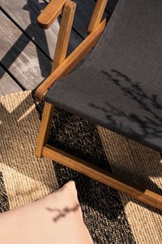 a chair sitting on top of a wooden deck next to a pillow and tree branch