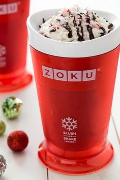 two red cups filled with ice cream and candy canes on top of a white table