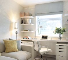 a living room with a couch, desk and shelves on the wall next to it