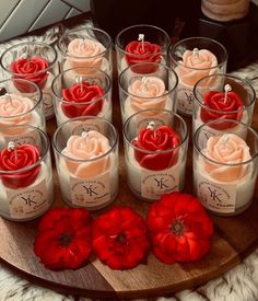 many candles are arranged on a wooden platter with red flowers in them and one candle is surrounded by smaller ones