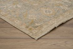 a beige and blue area rug on top of a wooden floor with an intricate design